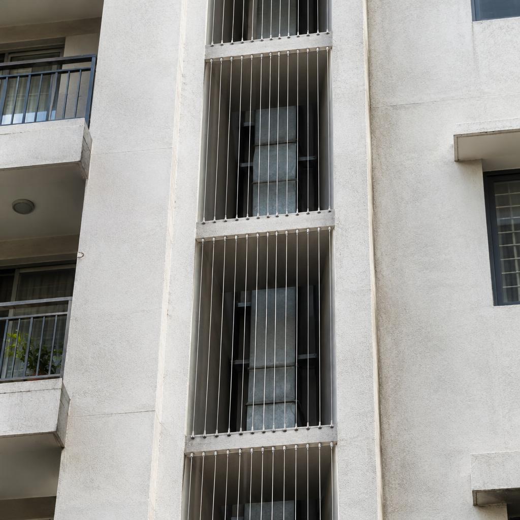 Apartment building ventilation duct shaft covered with vertical stainless steel invisible grill cables between floors